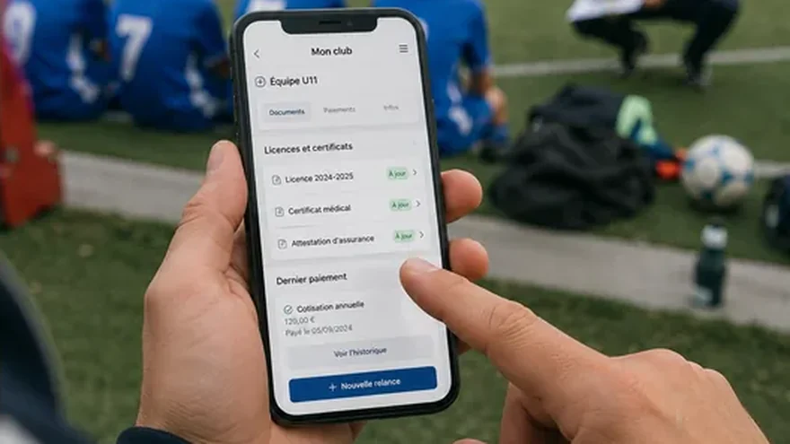 Au bord du terrain, un dirigeant de club consulte sur son téléphone les licences, certificats et cotisations de son équipe, tous à jour